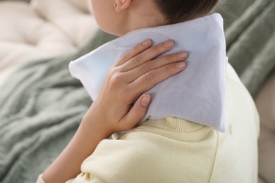 Photo of Woman using heating pad at home, closeup