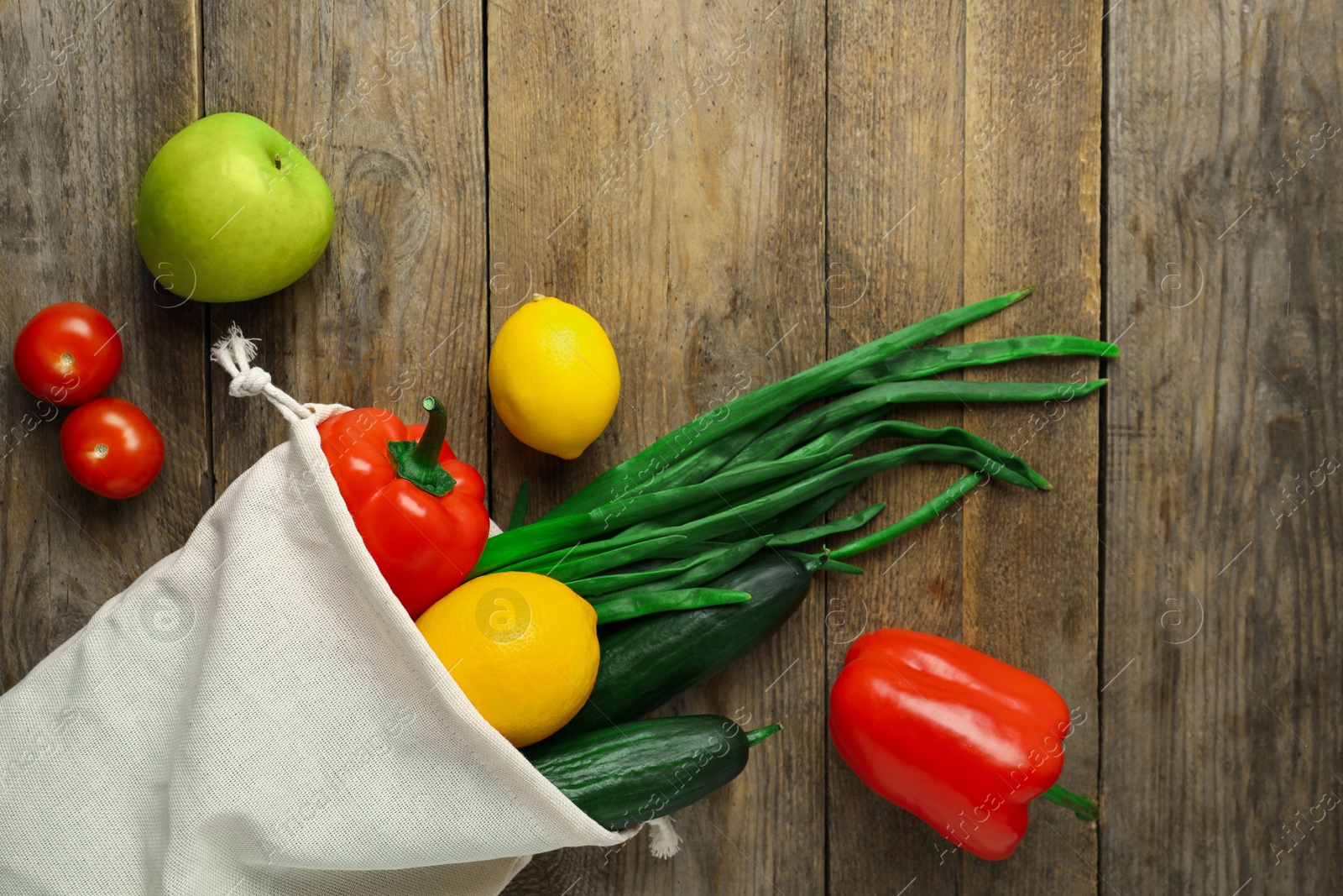 Photo of Cotton eco bag with vegetables and fruits on wooden table, flat lay