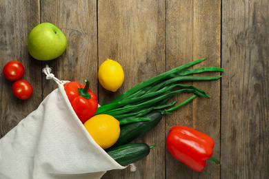 Cotton eco bag with vegetables and fruits on wooden table, flat lay