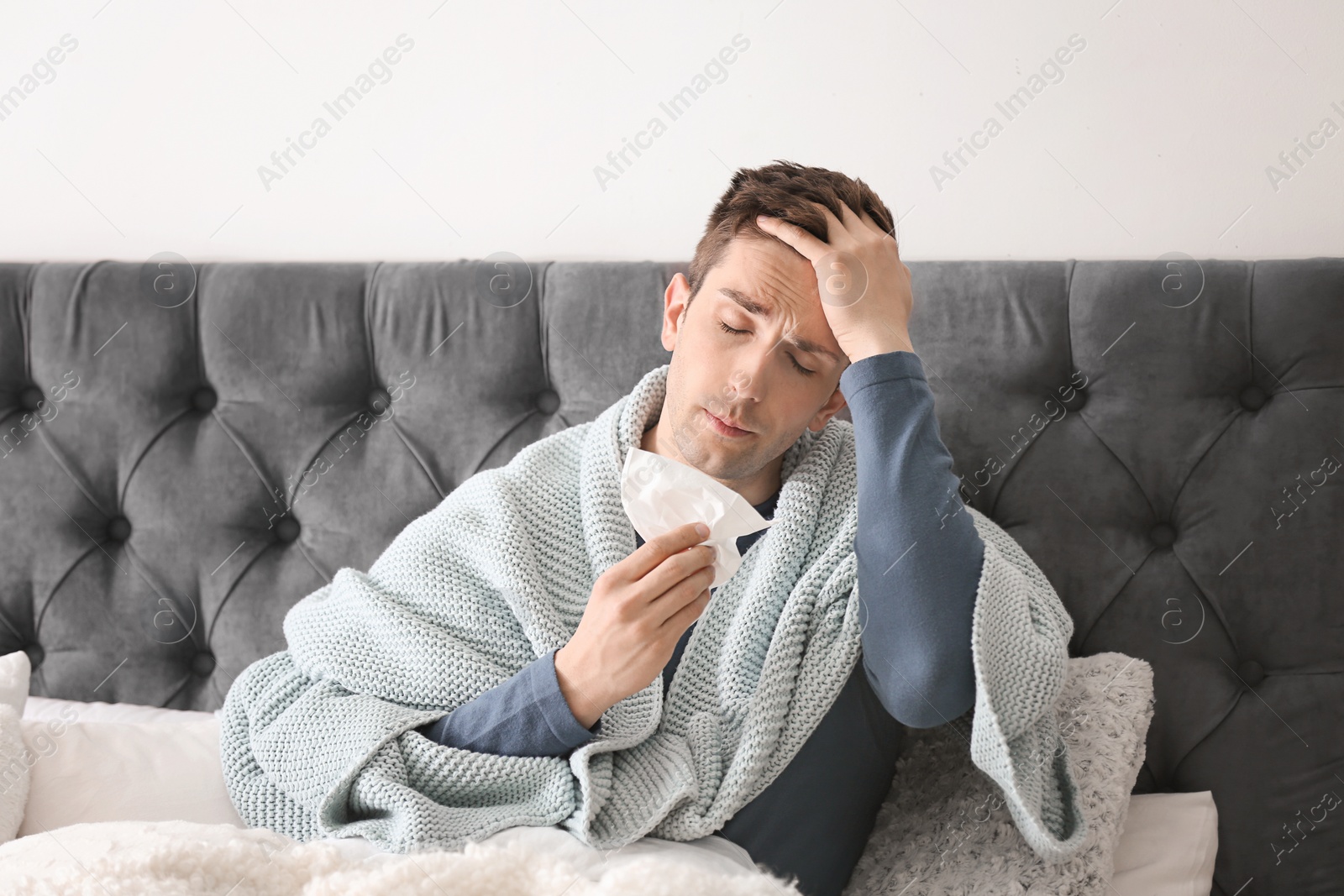 Photo of Sick young man with tissue suffering from cold in bed