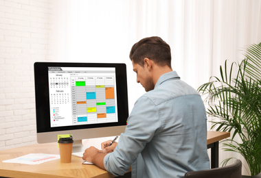 Photo of Handsome man using calendar app on computer in office