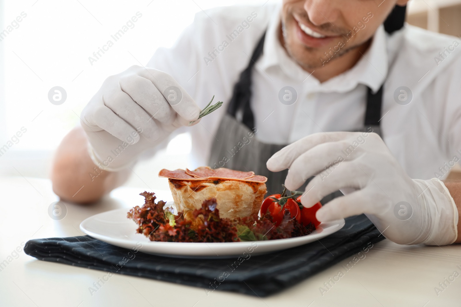 Photo of Professional chef presenting dish on table in kitchen, closeup