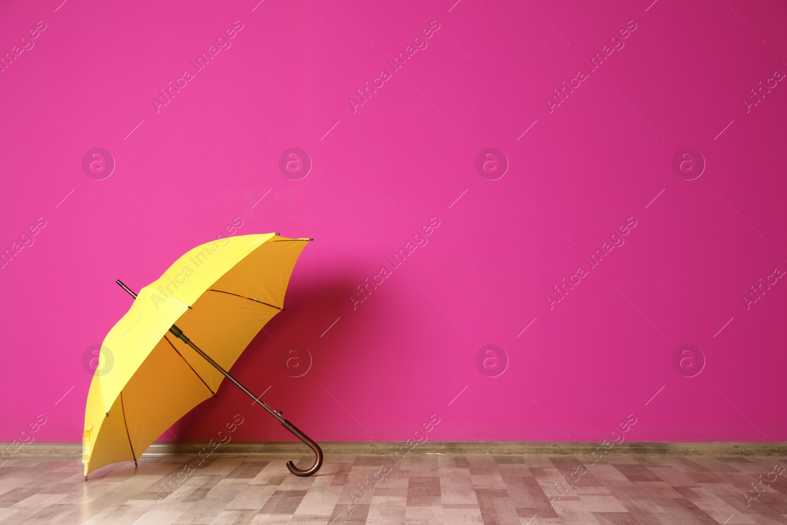 Photo of Beautiful open umbrella on floor near color wall with space for design