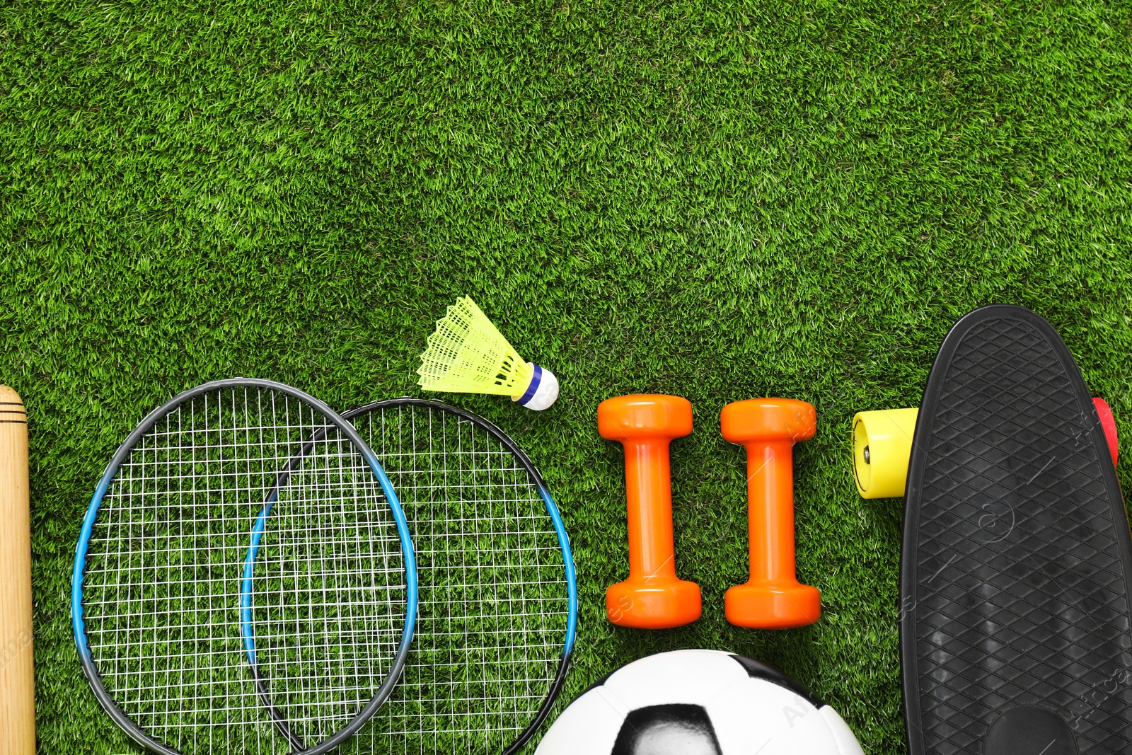 Photo of Different sports equipment on green grass, flat lay. Space for text