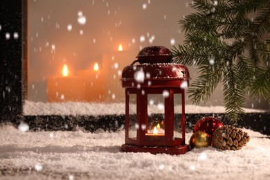 Photo of Snow falling onto window sill with Christmas lantern, outdoors. Space for text