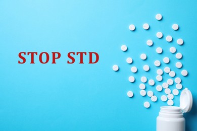 Image of Bottle with pills and text STOP STD on light blue background, flat lay