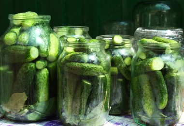 Photo of Glass jars with fresh ripe cucumbers on table. Pickling vegetables