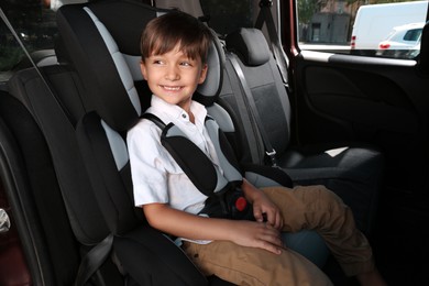Photo of Little boy fastened with car safety belt in child seat