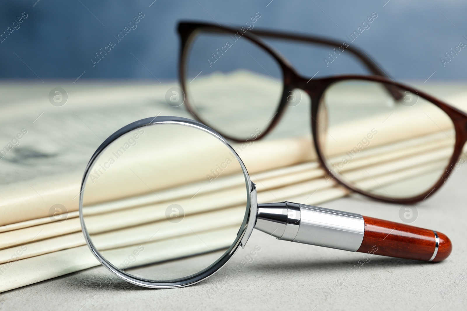 Photo of Stack of newspapers, magnifier and glasses on table. Search concept