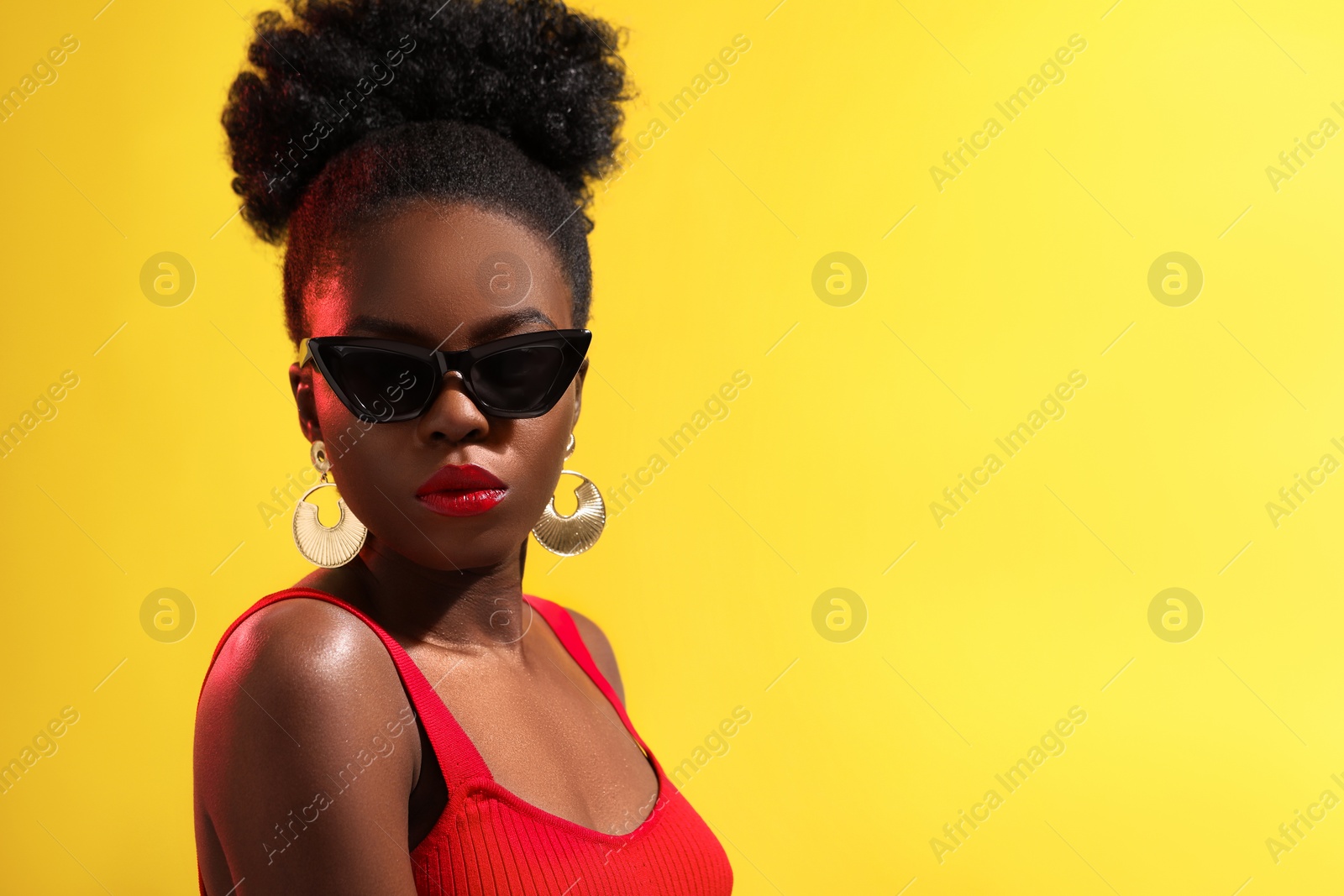 Photo of Fashionable portrait of beautiful woman with stylish sunglasses on yellow background, space for text
