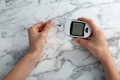 Photo of Woman using glucometer at table. Diabetes test