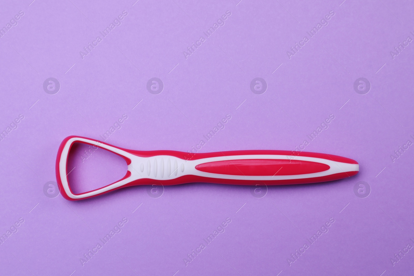 Photo of Red tongue cleaner on violet background, top view