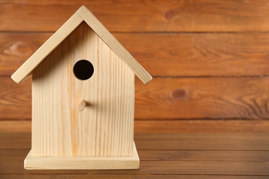 Photo of Beautiful bird house on wooden table, space for text