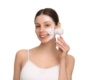 Young woman washing face with brush and cleansing foam on white background