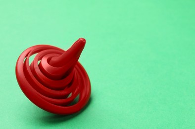 Photo of One red spinning top on green background, closeup. Space for text