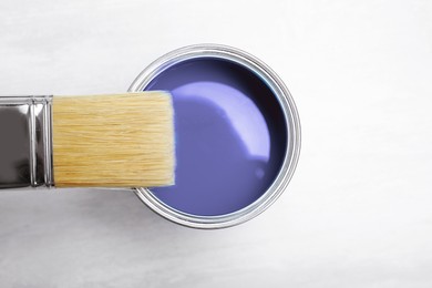 Image of Tin can with violet paint and brush on white background, top view