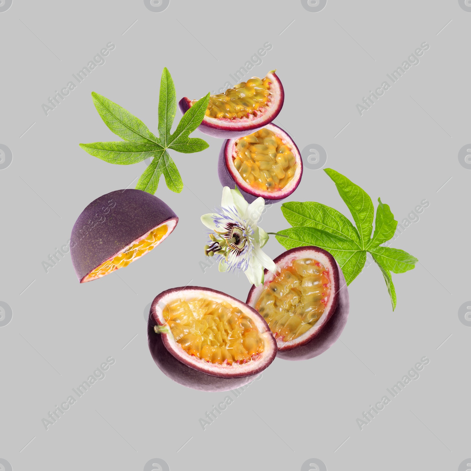 Image of Tasty passion fruits, passiflora leaves and flower falling on light grey background