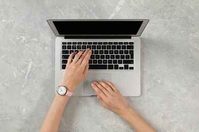 Woman using modern laptop at marble table, top view