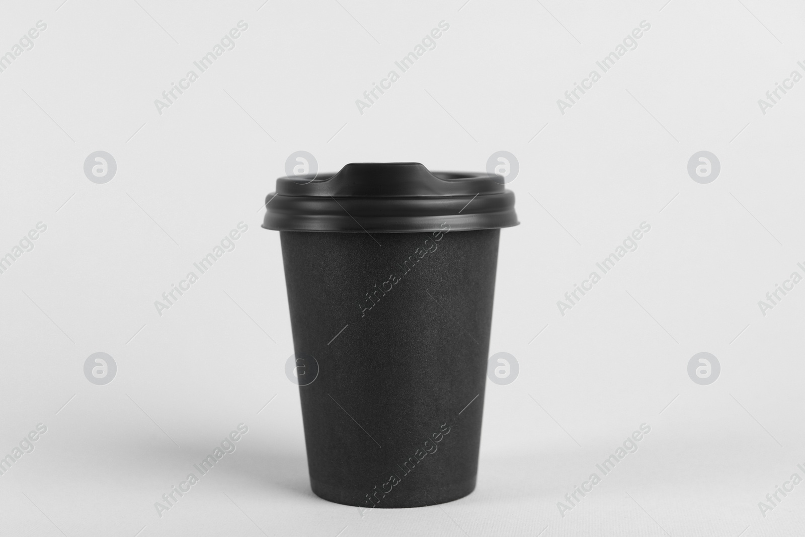 Photo of Black paper cup with plastic lid on light background. Coffee to go