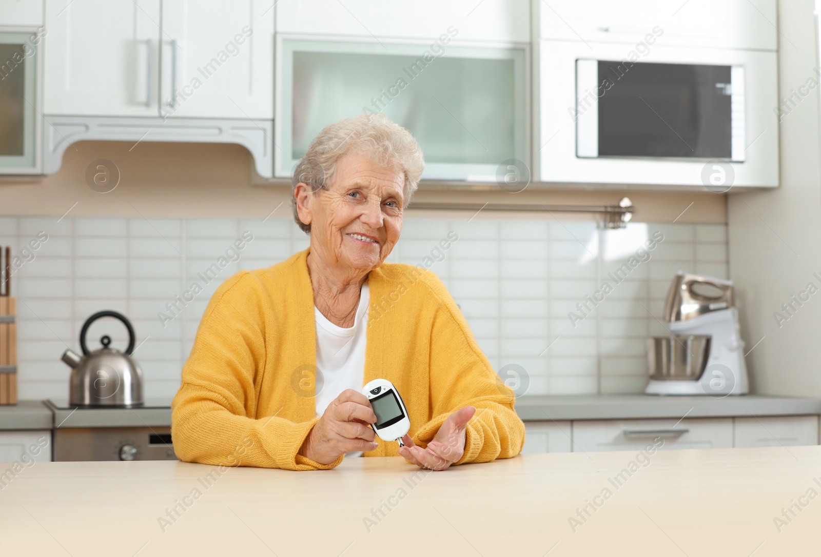 Photo of Senior woman using digital glucometer at home. Diabetes control