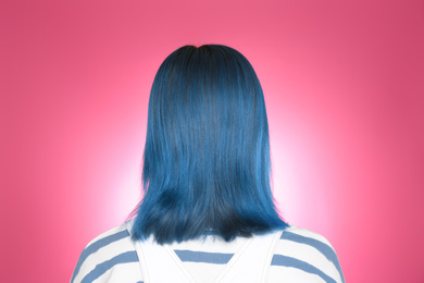 Photo of Woman with bright dyed hair on pink background, back view