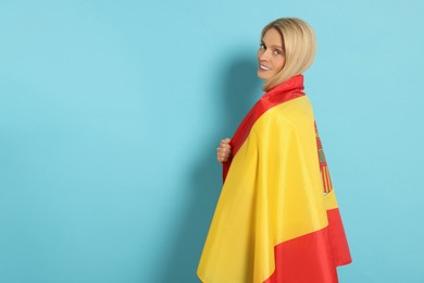 Photo of Woman with flag of Spain on light blue background, space for text
