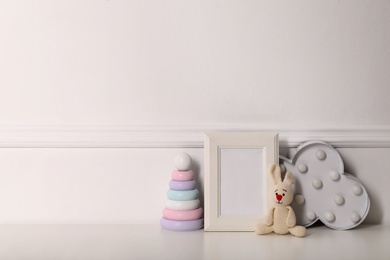 Photo of Empty photo frame, cute toys and decor near wall, space for text. Baby room interior element