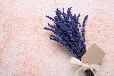 Photo of Bouquet of beautiful preserved lavender flowers with blank tag and ribbon on color textured table, top view. Space for text