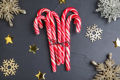 Sweet candy canes and Christmas decor on black background, flat lay