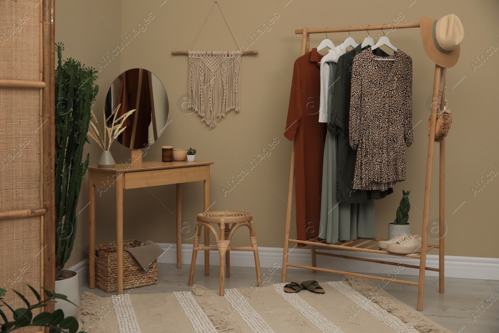 Photo of Modern dressing room interior with clothing rack, wooden table and mirror