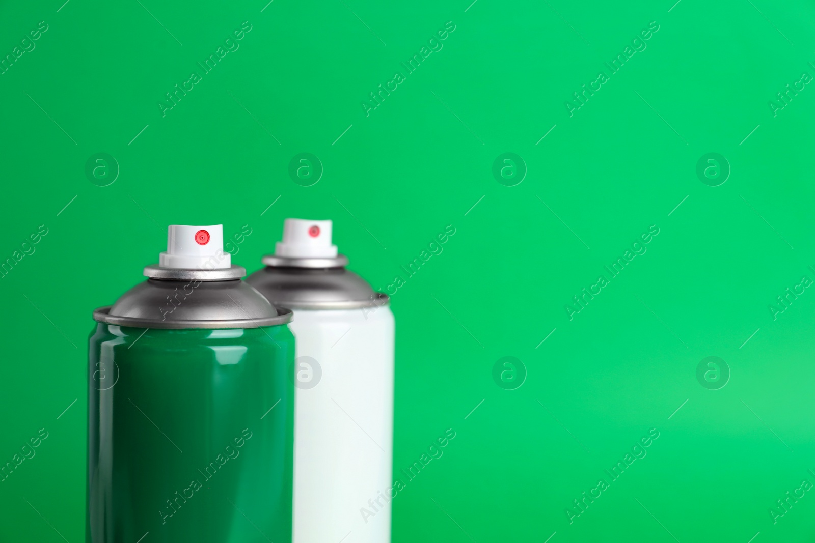 Photo of Two cans of spray paints on green background. Space for text