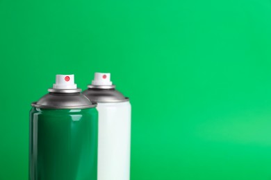 Photo of Two cans of spray paints on green background. Space for text