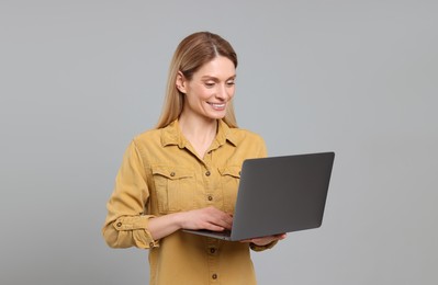 Happy woman with laptop on light grey background