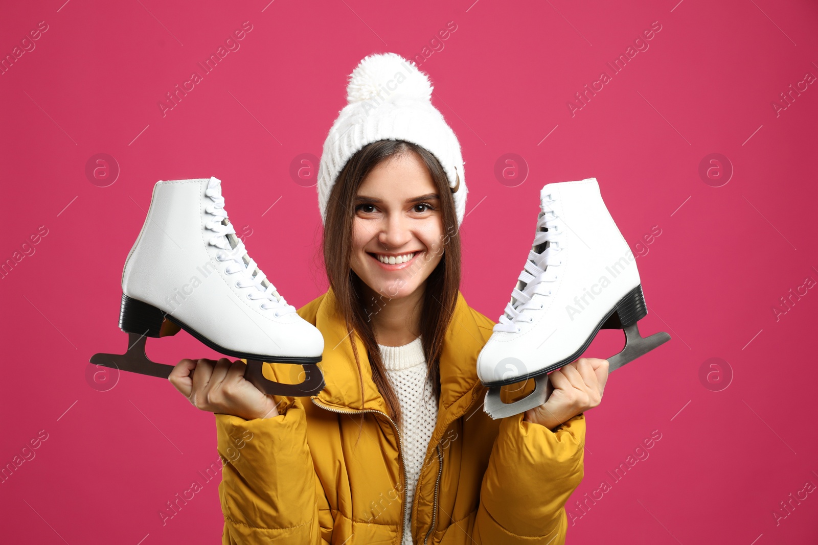 Photo of Happy woman with ice skates on pink background