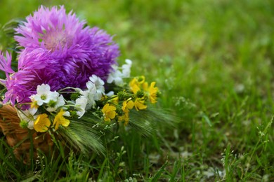 Photo of Bouquet of beautiful wildflowers on green grass outdoors, closeup. Space for text