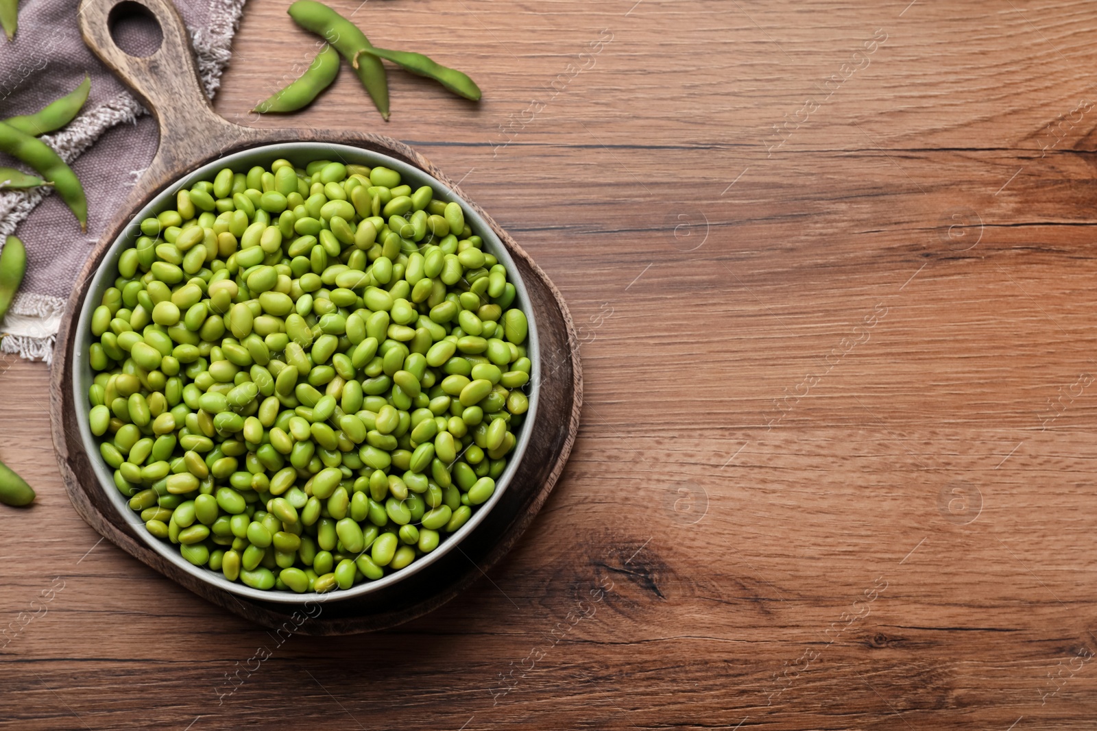 Photo of Organic edamame beans on wooden table, flat lay. Space for text