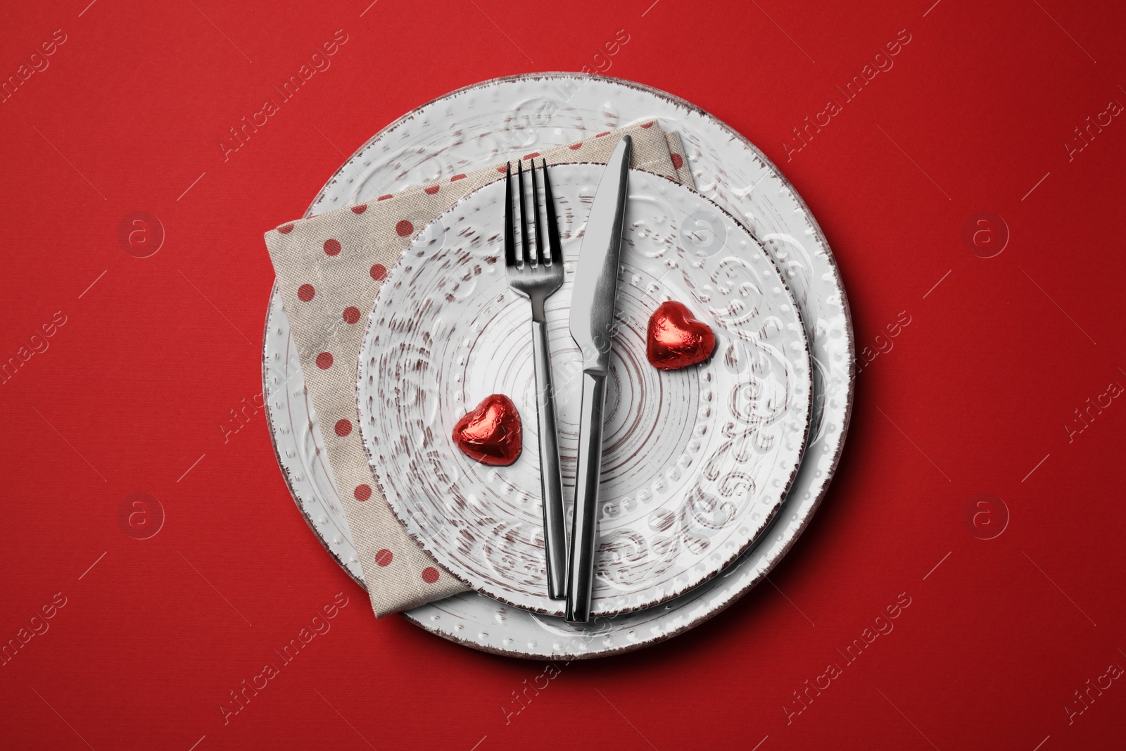 Photo of Beautiful place setting with dishware and sweets for romantic dinner on red table, top view