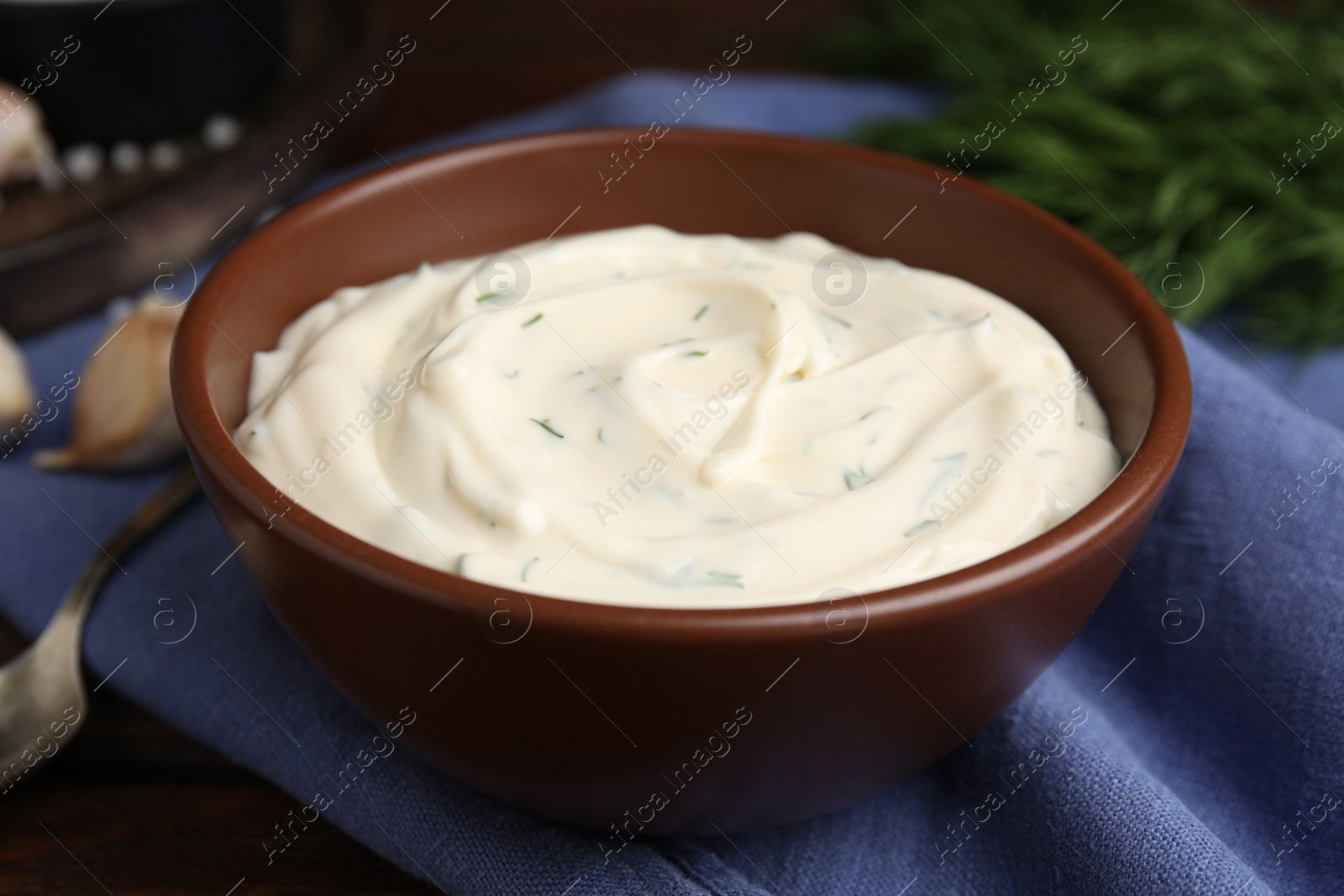 Photo of Tasty creamy dill sauce in bowl on blue kitchen towel, closeup