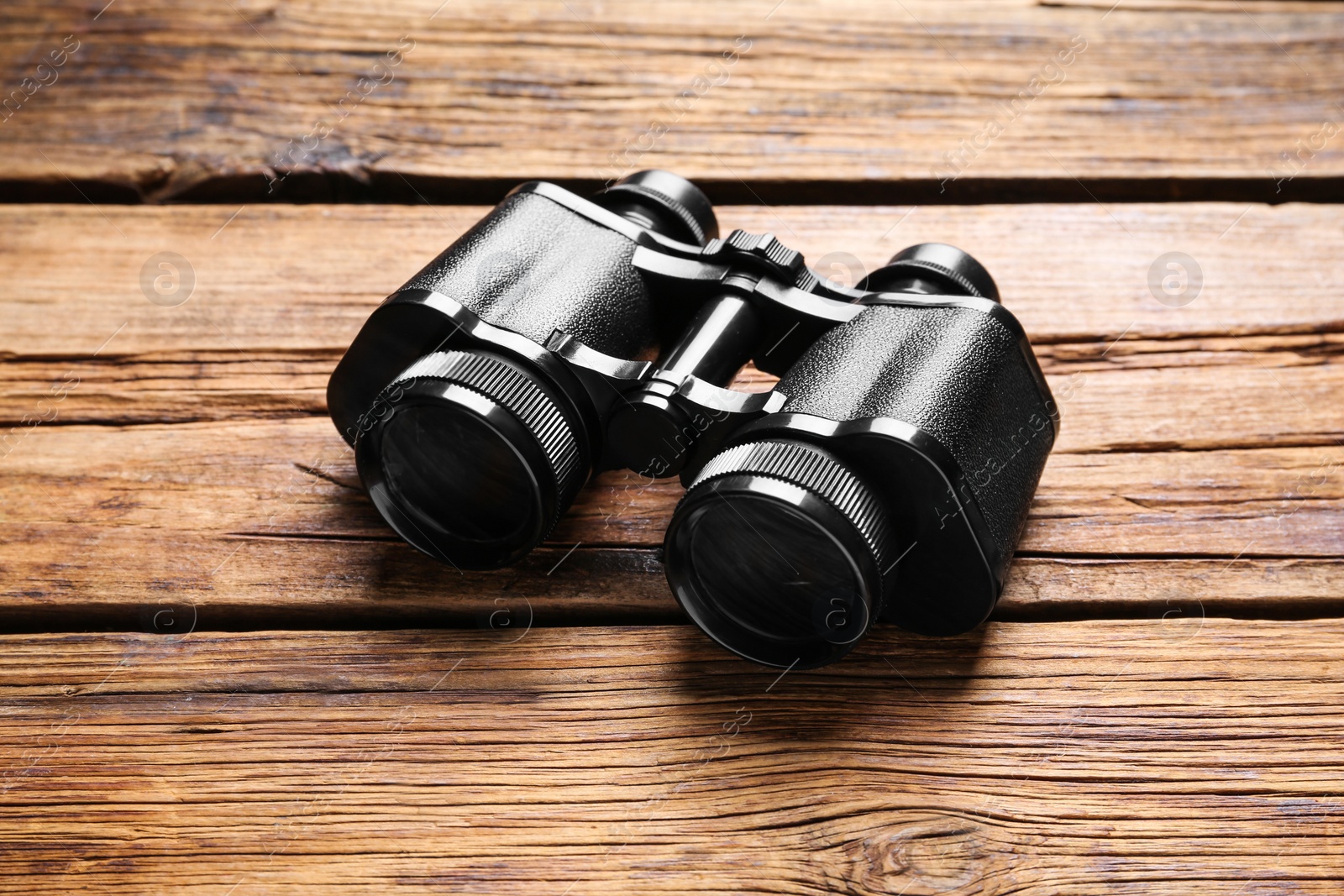 Photo of New binoculars on wooden table. Optical instrument