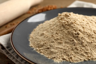 Photo of Plate with buckwheat flour on wooden table, closeup