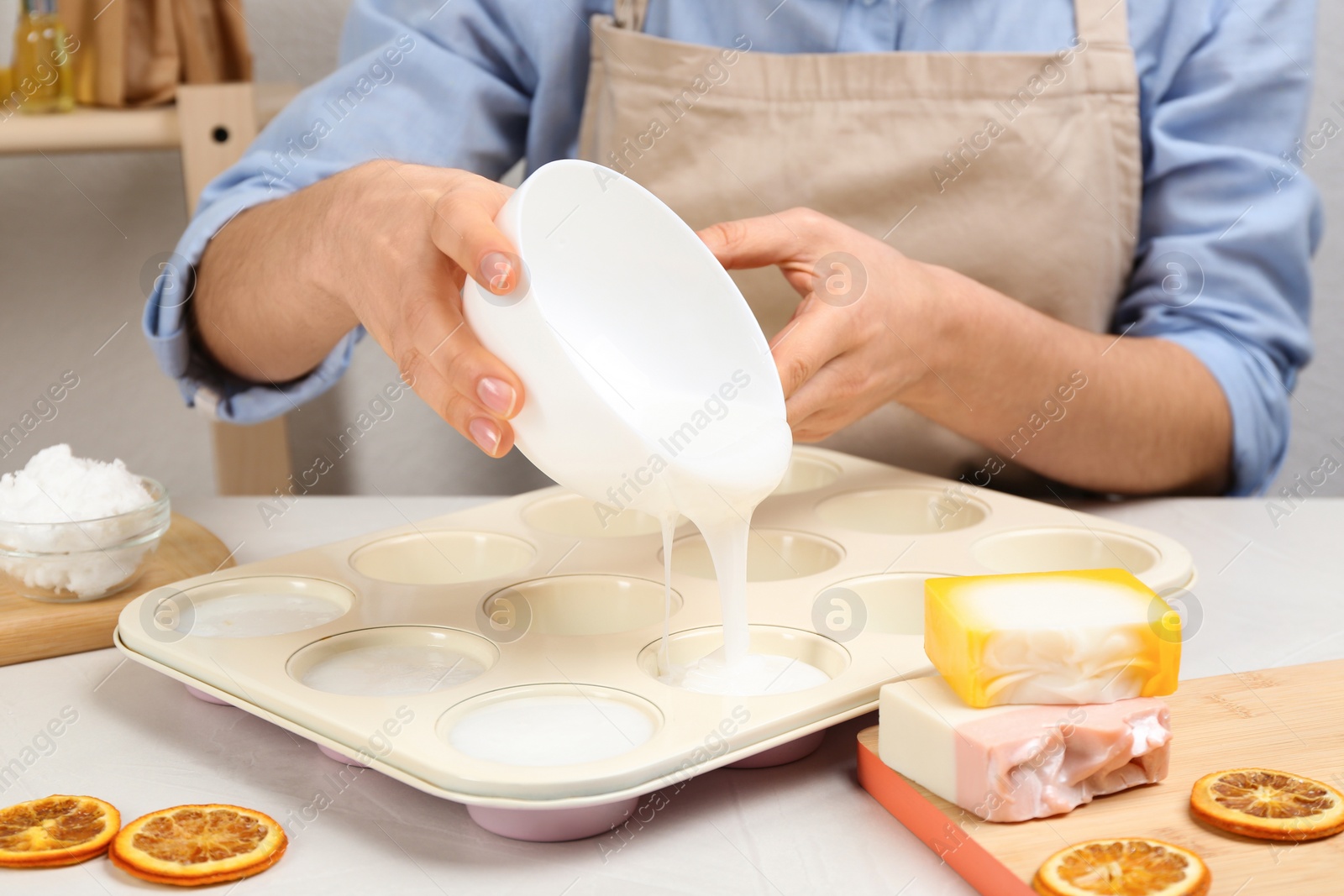 Photo of Woman making natural handmade soap at white table, closeup