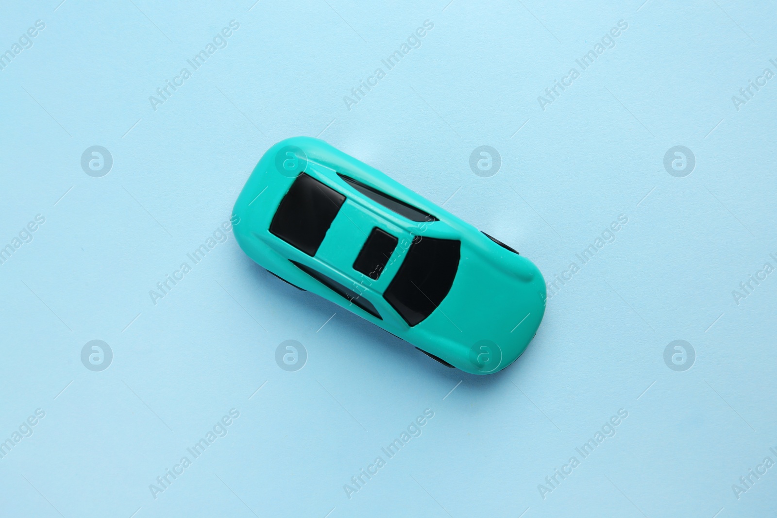 Photo of One bright car on light blue background, top view. Children`s toy