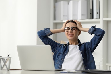 Photo of Woman suffering from headache at workplace in office