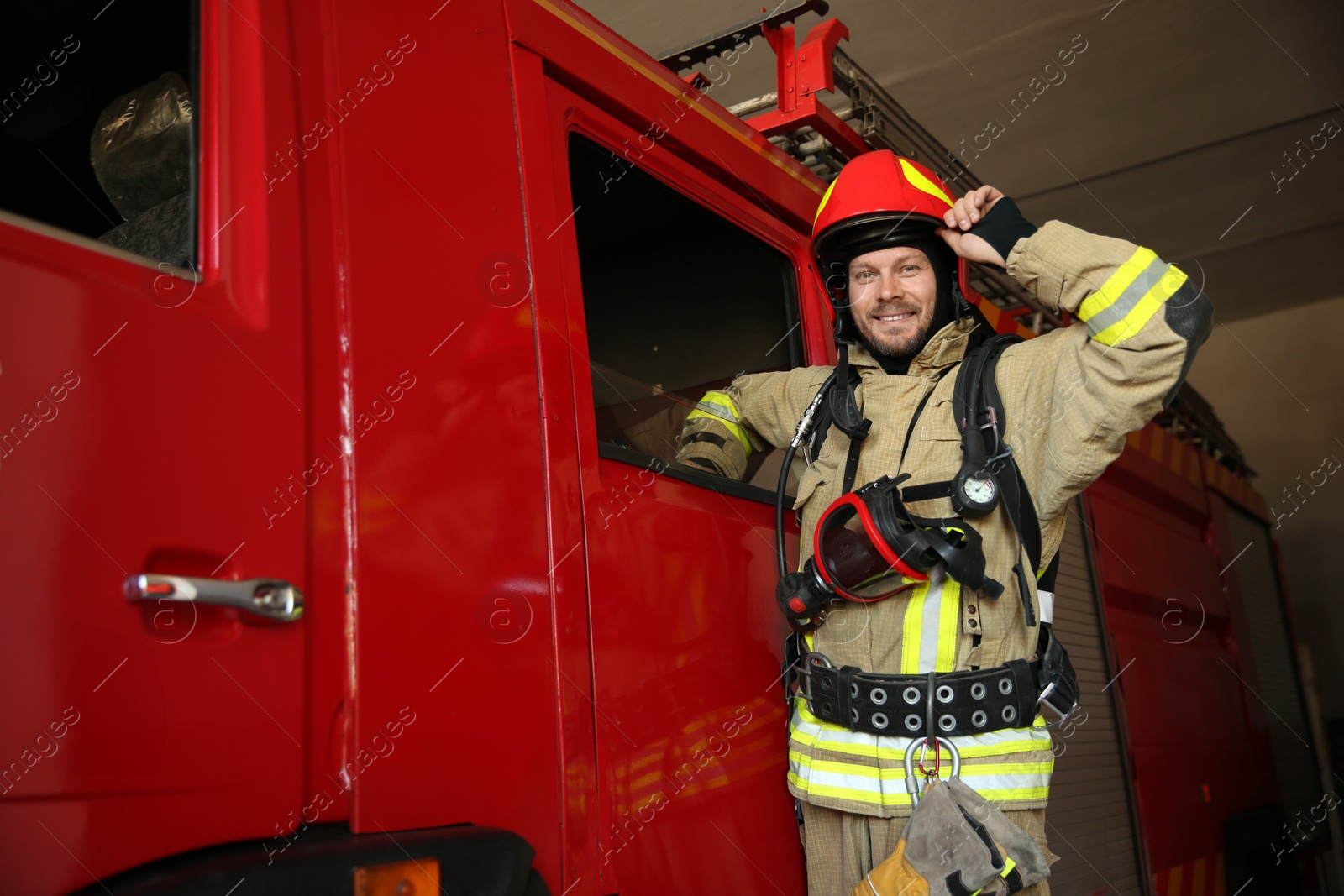 Photo of Portrait of firefighter in uniform near red fire truck at station