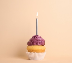 Photo of Birthday cupcake with candle on beige background