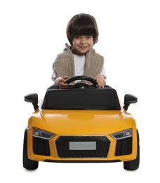 Cute little boy driving children's electric toy car on white background