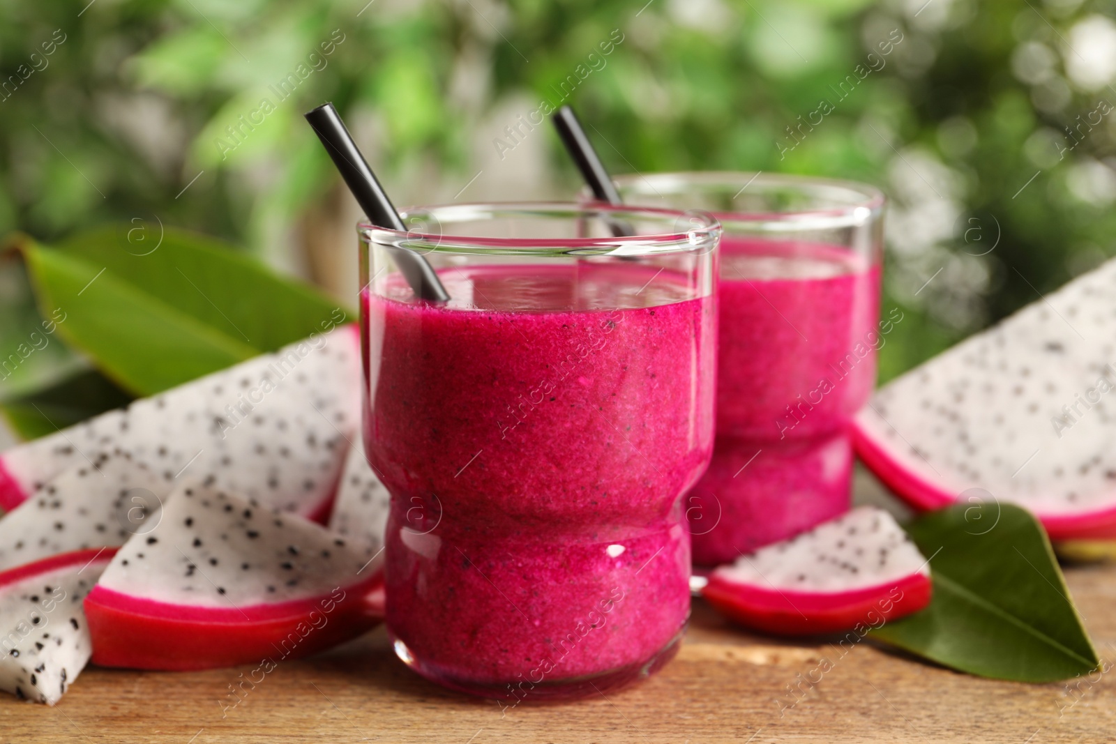 Photo of Delicious pitahaya smoothie and fresh fruits on wooden table, closeup