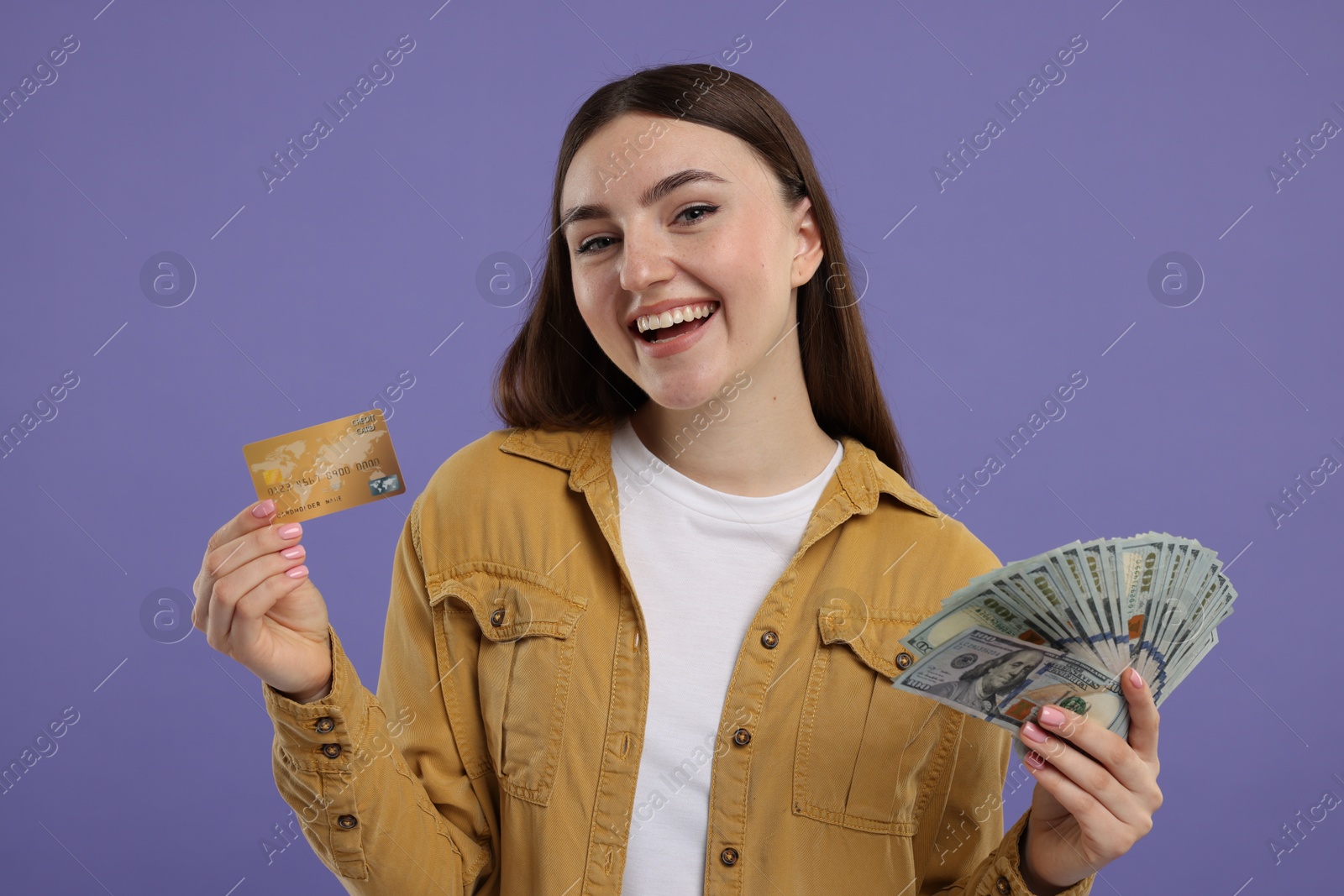 Photo of Happy woman with credit card and dollar banknotes on purple background