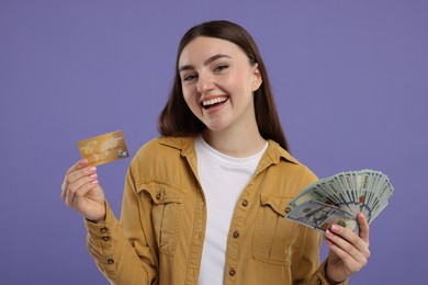 Photo of Happy woman with credit card and dollar banknotes on purple background