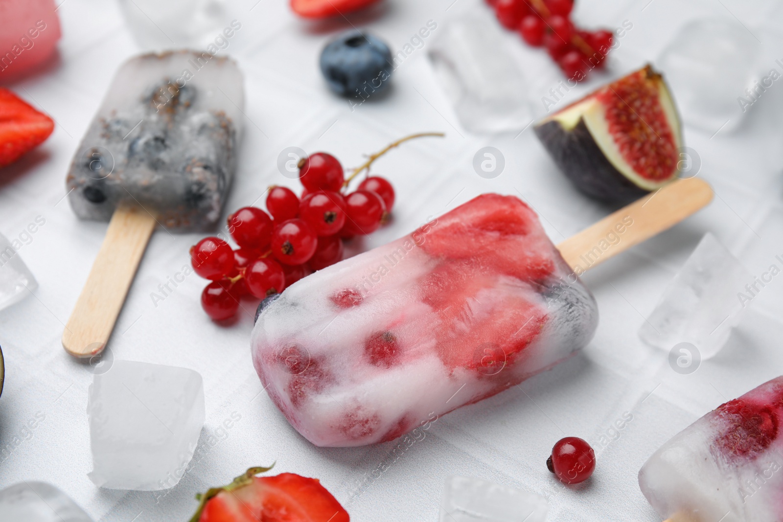 Photo of Tasty refreshing berry ice pops on white table, closeup